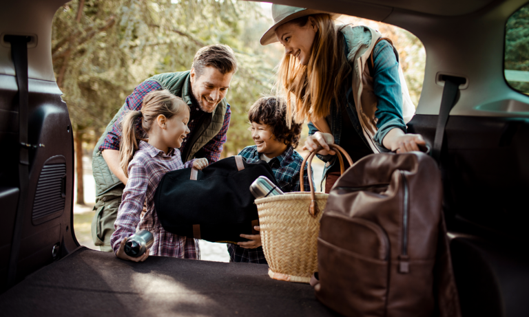 A young couple and their two young children share a laugh while packing the trunk of their car before heading off to a Thanksgiving dinner.
