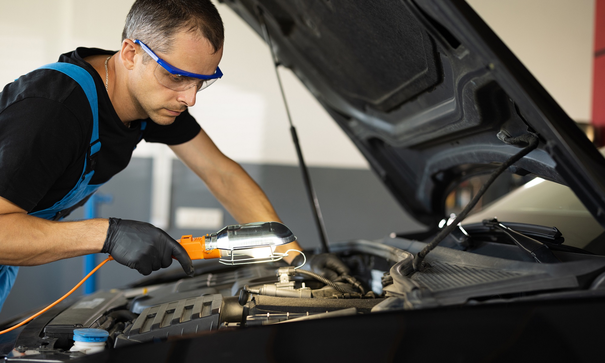 Mechanic in overalls working on a car for it's check engine light