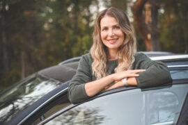 Adult woman standing outside of car learning about the cost of car ownership over time