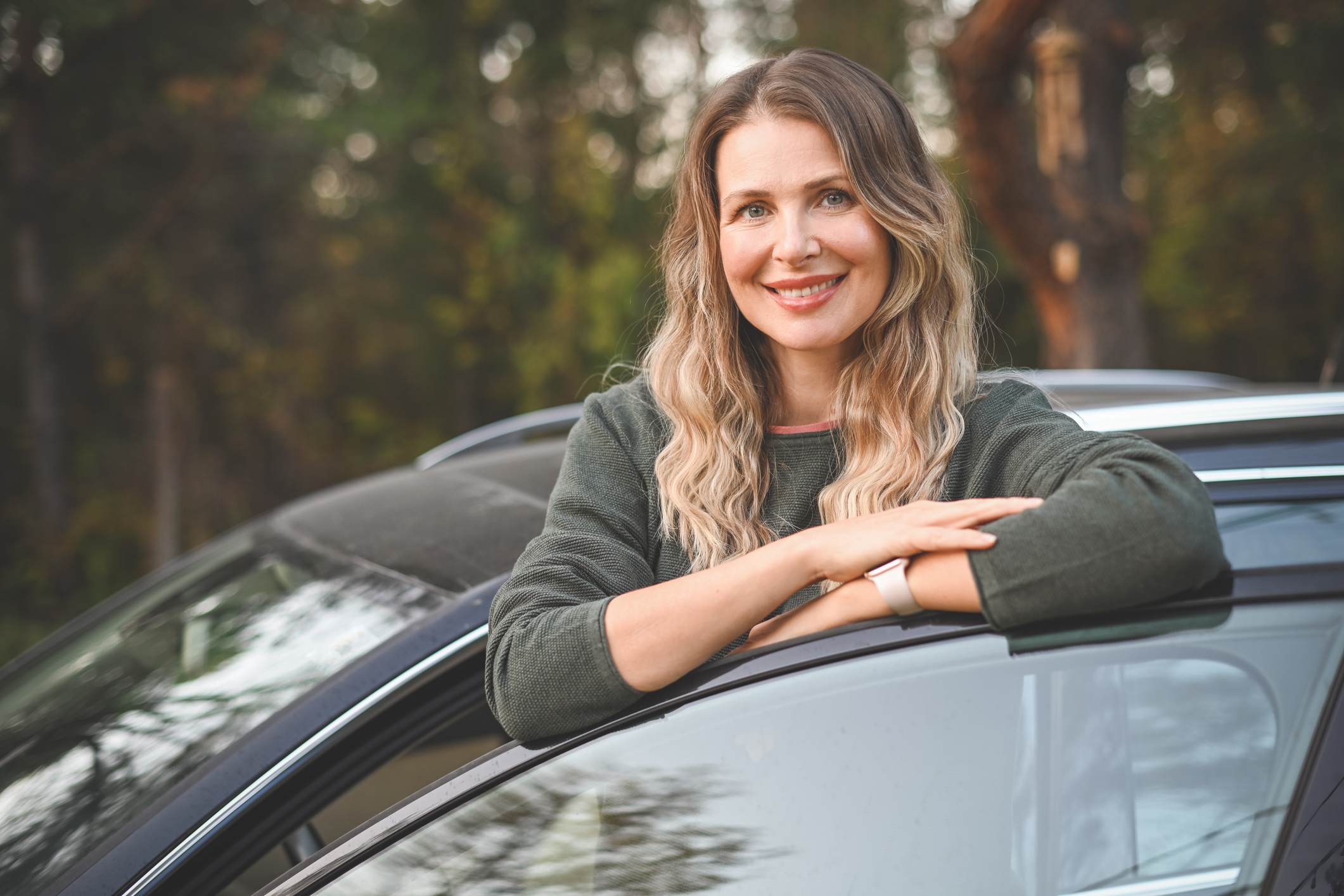 Adult woman standing outside of car learning about the cost of car ownership over time