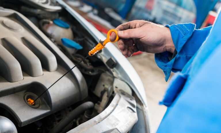 Mechanic checking oil status with dipstick