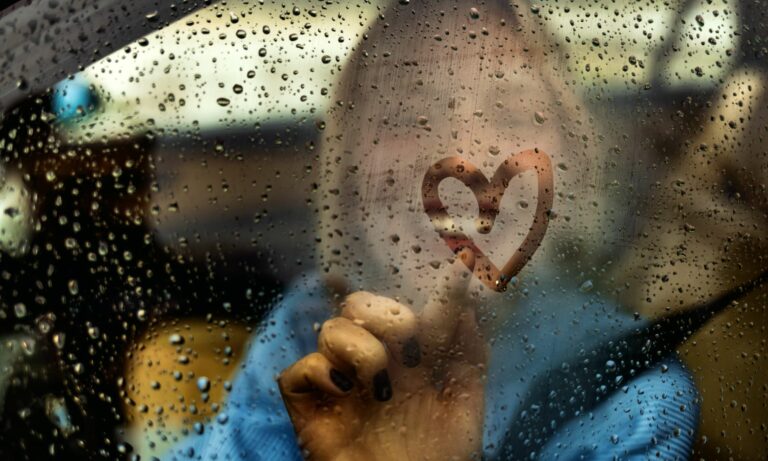 Woman drawing heart on car window for Valentine's Day