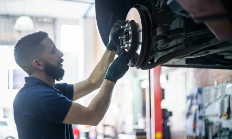 Mechanic checking the brake disk of a car on lift at the workshop