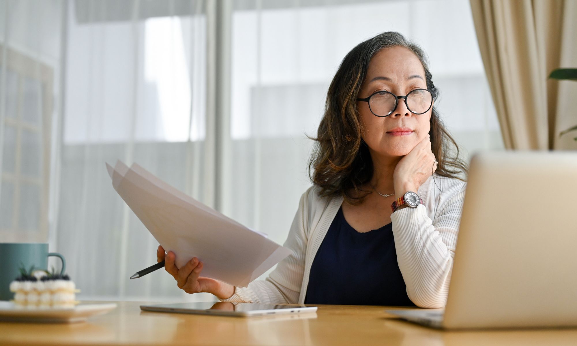 Woman sitting at desk comparing extended warranty paperwork