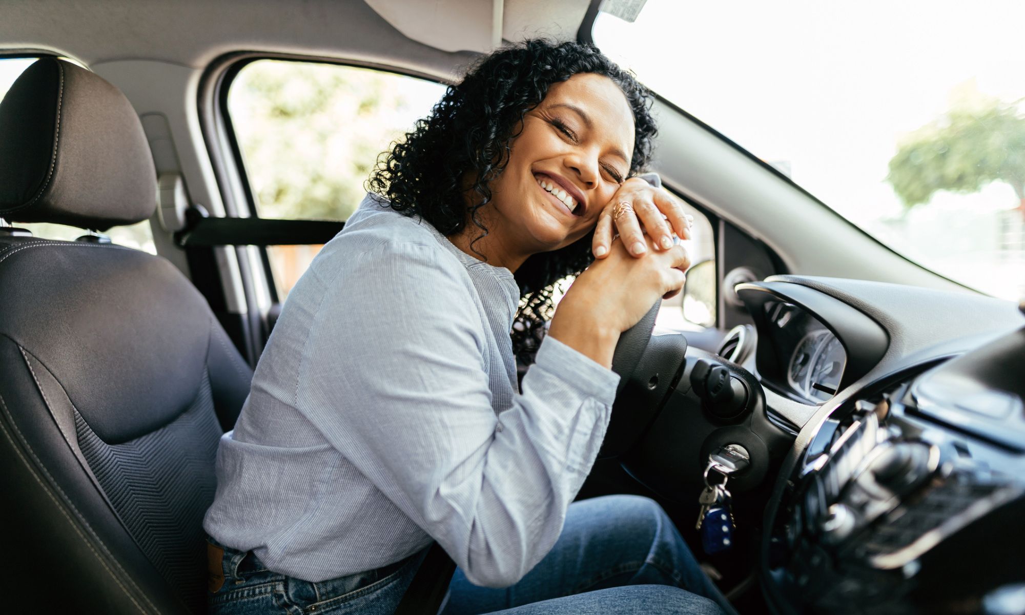 Woman in car hugging steering wheel