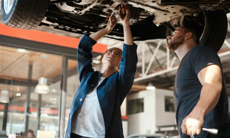 Two mechanics working on the underside of a car