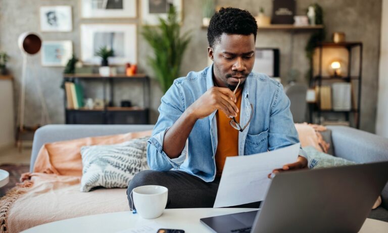 Man looking at car recall letter in front of computer