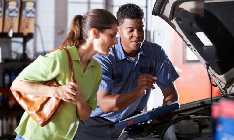 Auto mechanic with a female customer looking under car hood