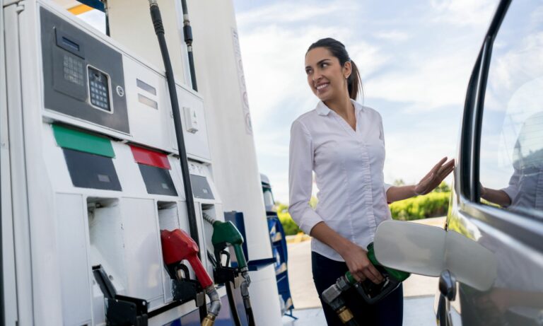 Woman refueling her car at a gas station and holding the fuel pump