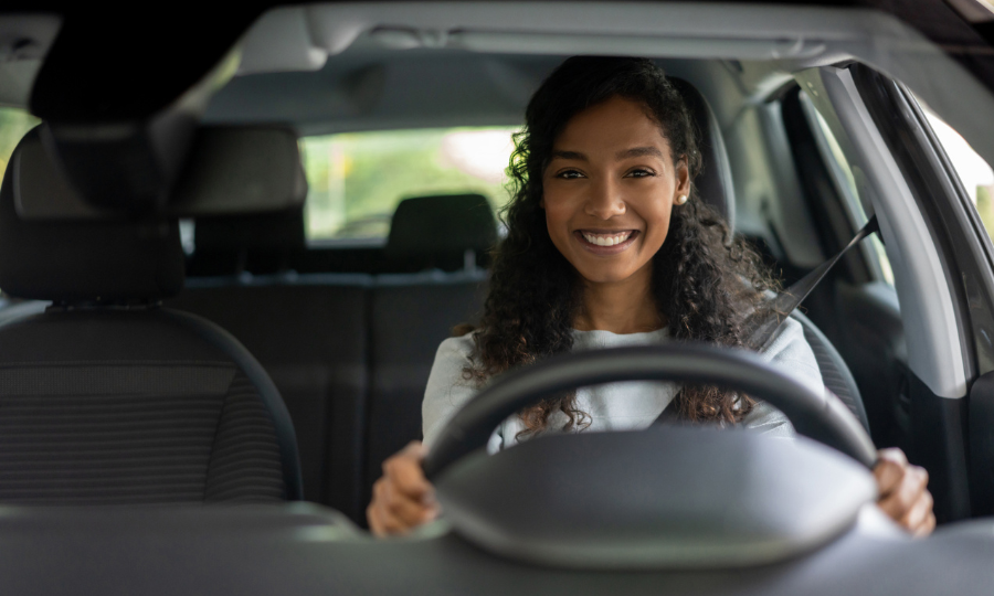 Mujer que parece muy feliz conduciendo un coche y sonriendo.