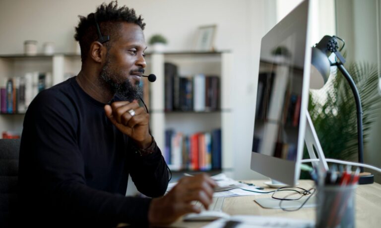 Customer service agent talking on a headset at his desk