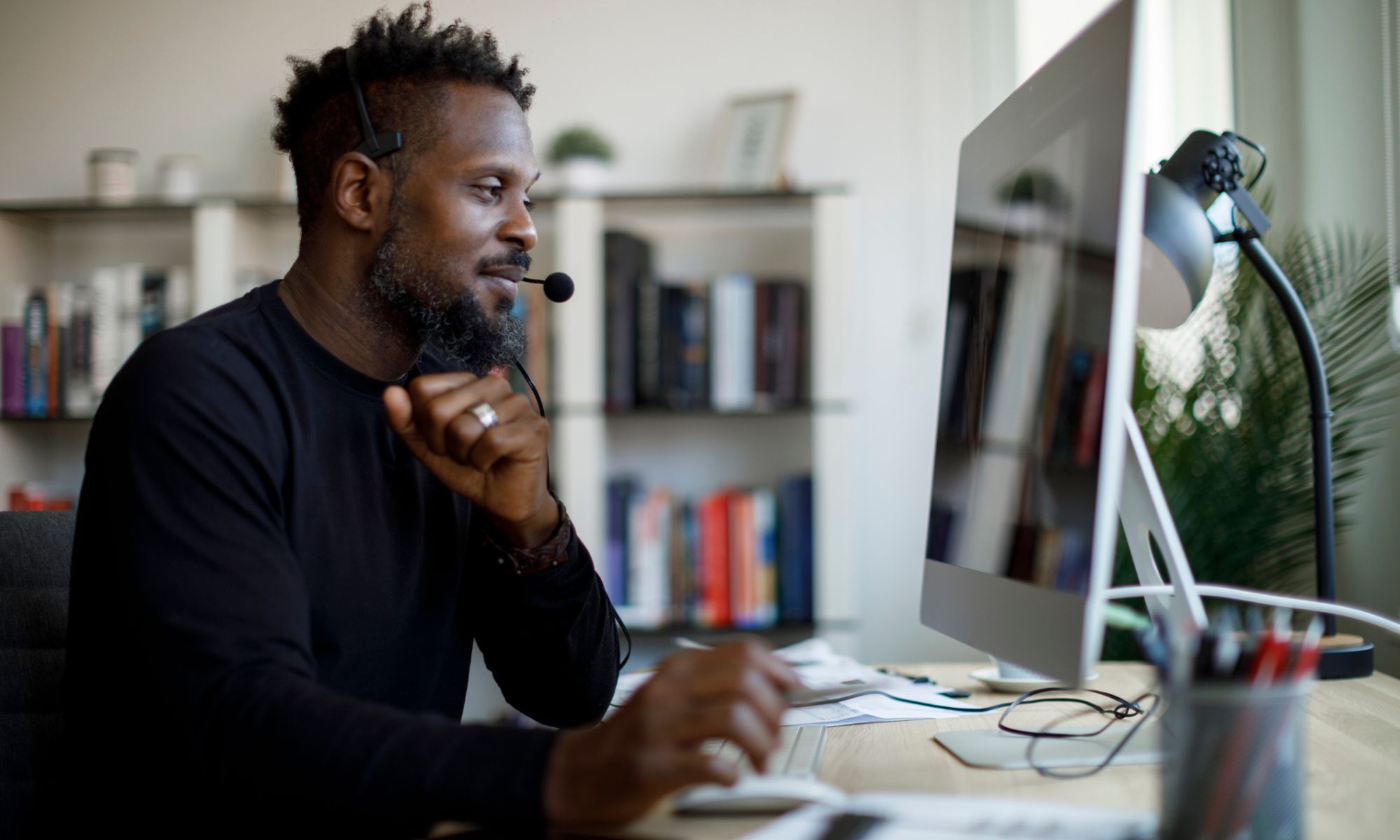 Customer service agent talking on a headset at his desk