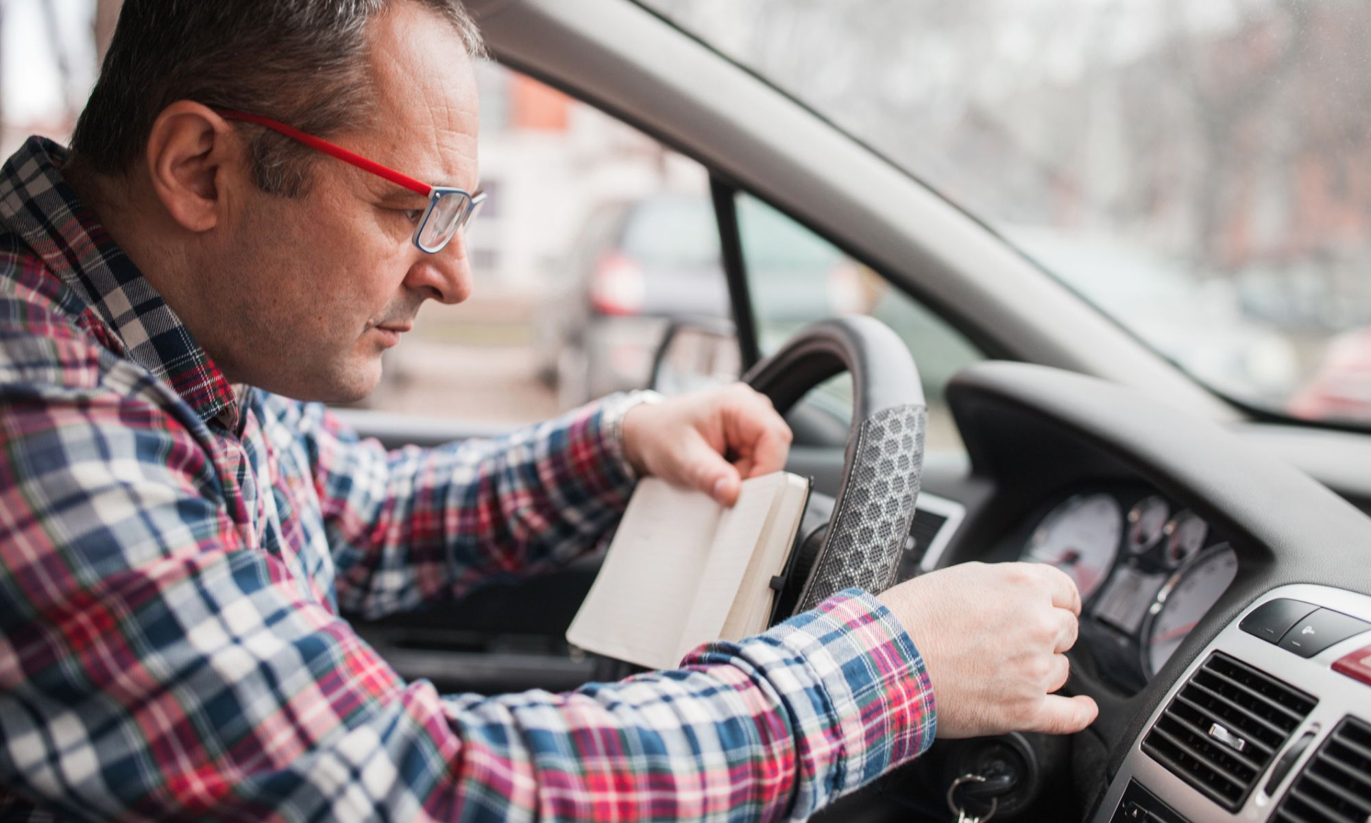 Car driver sitting in the car and taking notes about the odometer