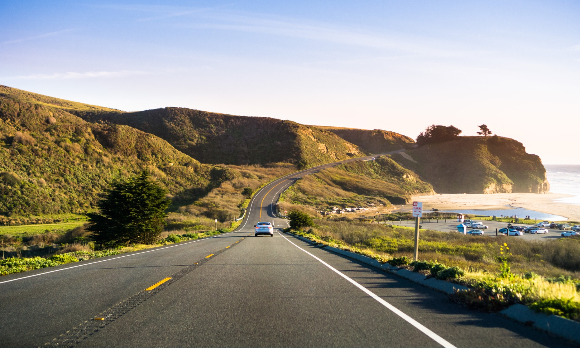 A car driving on Highway 1 on the California coastline