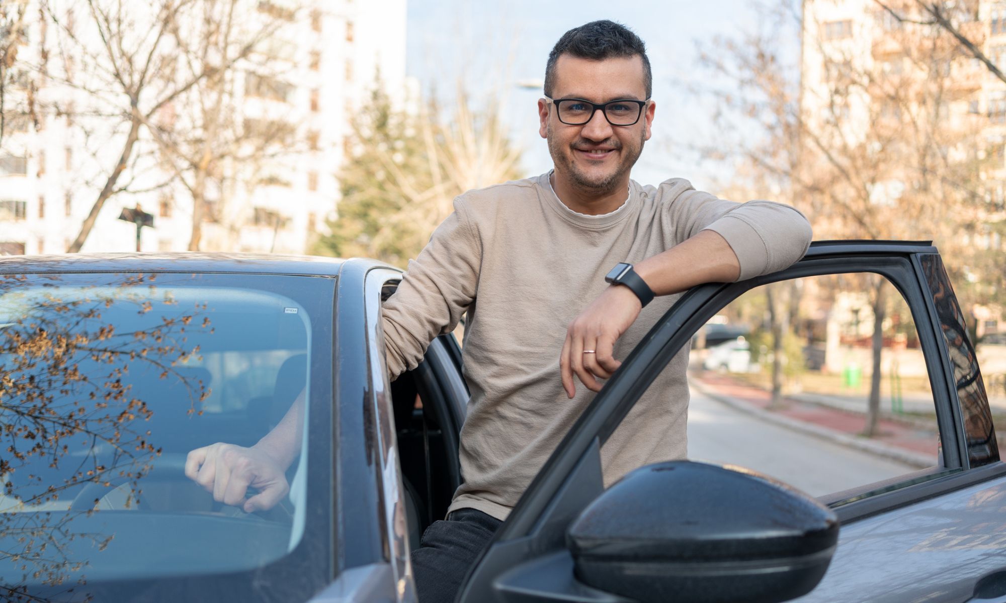 Man standing and leaning on his car door