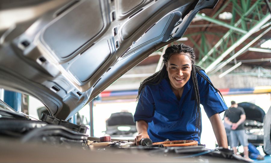 Woman technician repairing a car in auto repair shop
