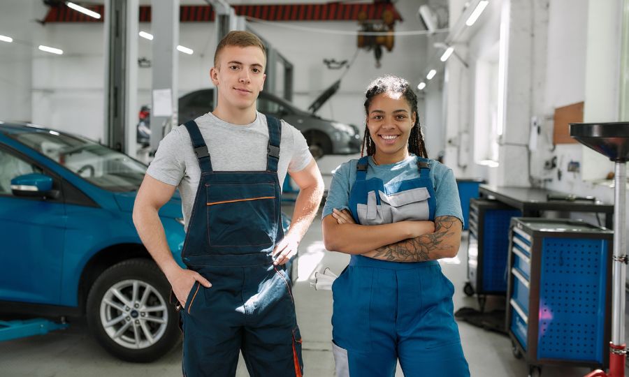 Professional female and male mechanic smiling at camera