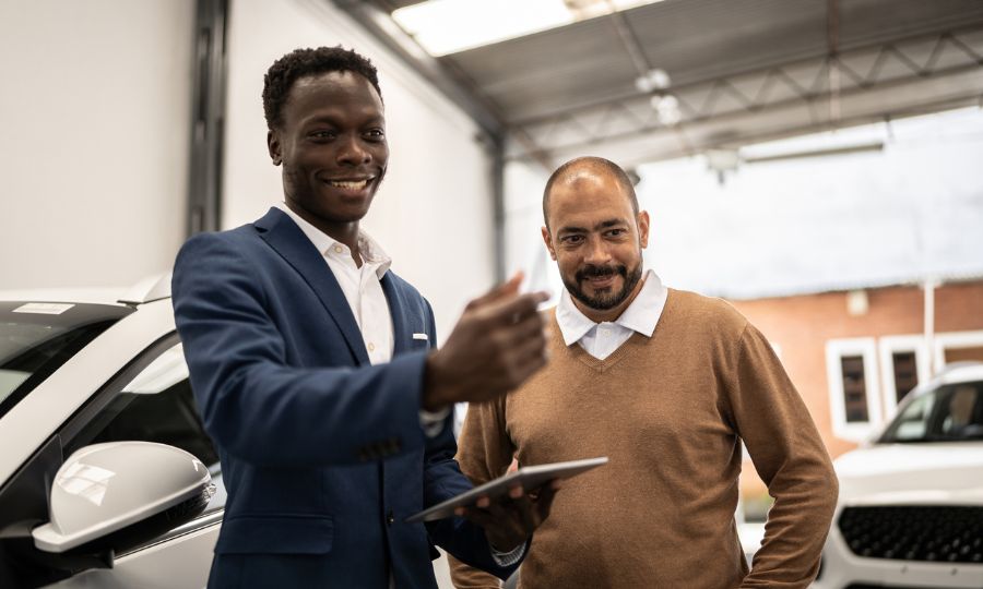 Salesman showing car to customer in a car dealership