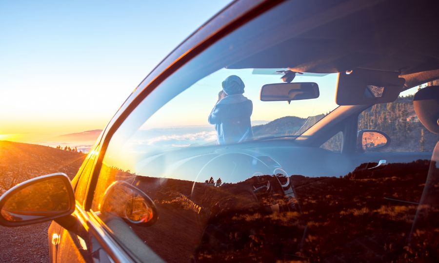 Woman photographing landscape standing near the car