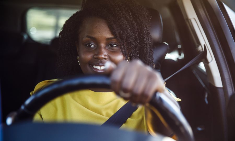Smiling young woman sitting behind the wheel