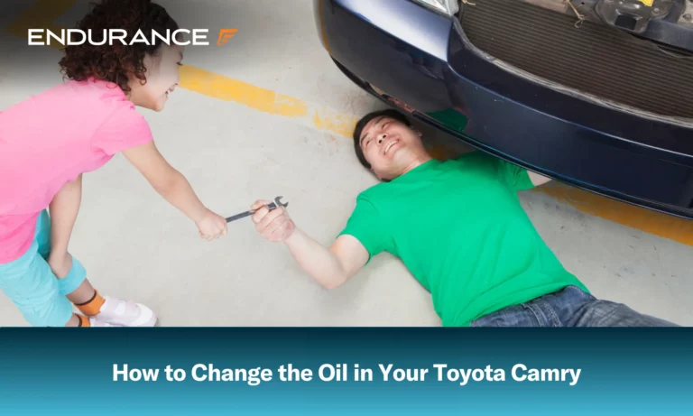 Girl handing her father a wrench as he changes the oil in his car