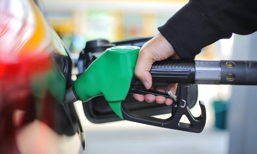 Close up of a hand holding a green gasoline fuel nozzle