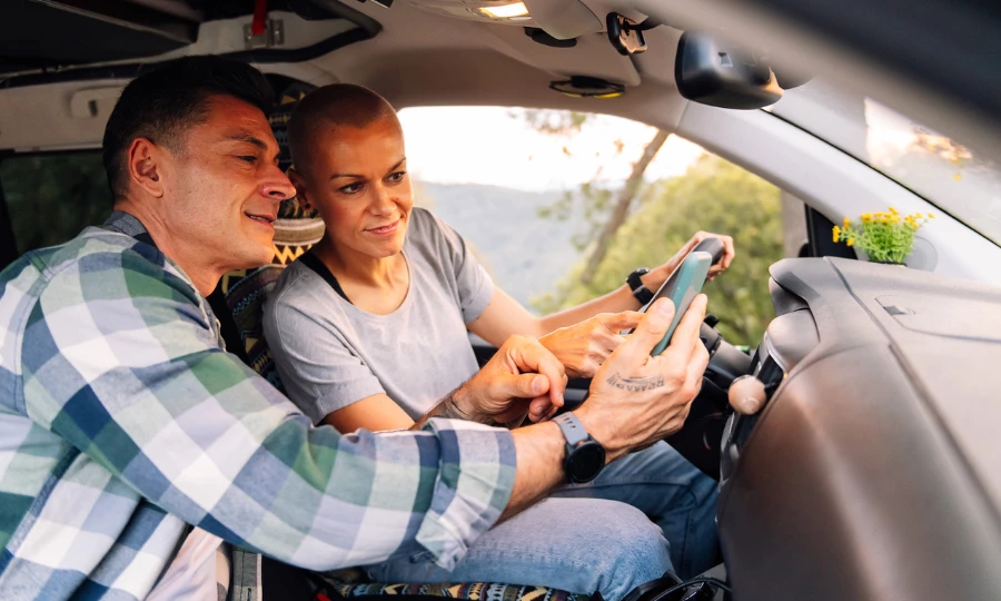 Couple planning on phone the route in a car