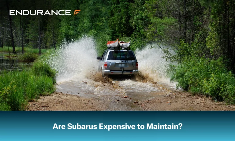 A Subaru, with two kayaks, drivers through a washed out dirt road