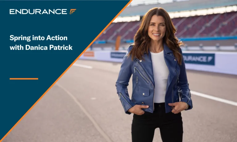 Racecar driver Danica Patrick standing on a race track with an Endurance sign in the background