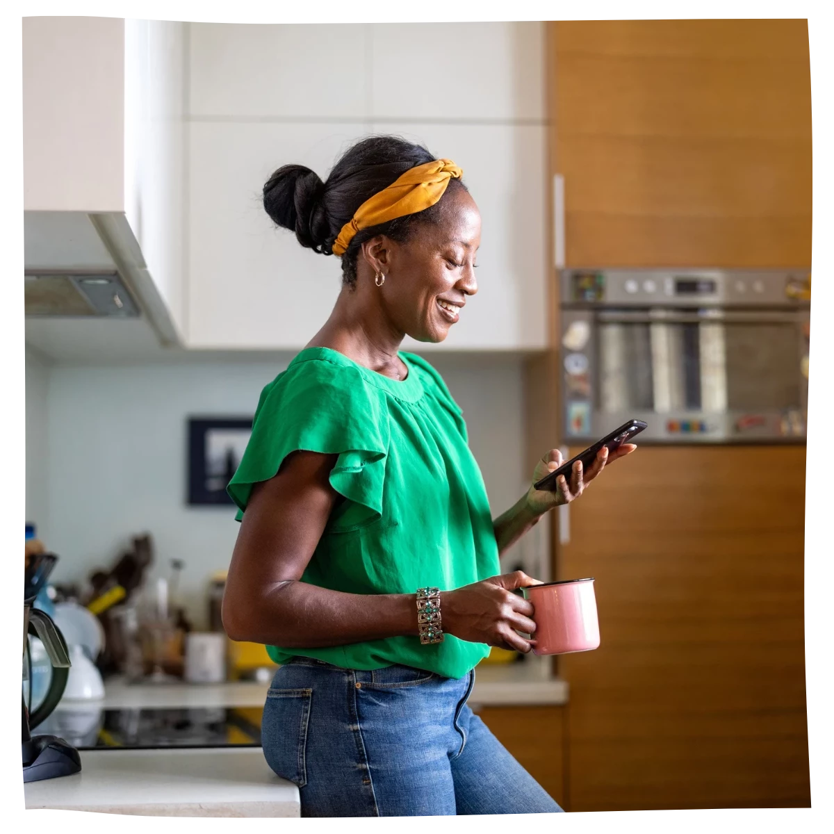 Una mujer mirando su teléfono inteligente en la cocina.