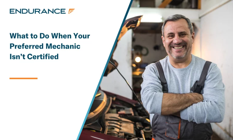 Smiling older male mechanic standing in front of a car
