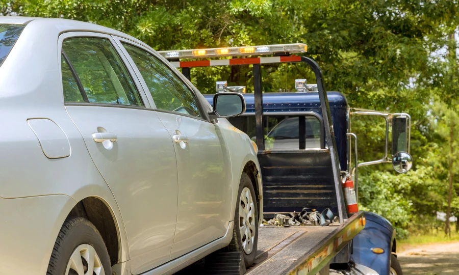 A tow truck from roadside assistance towing away a silver car