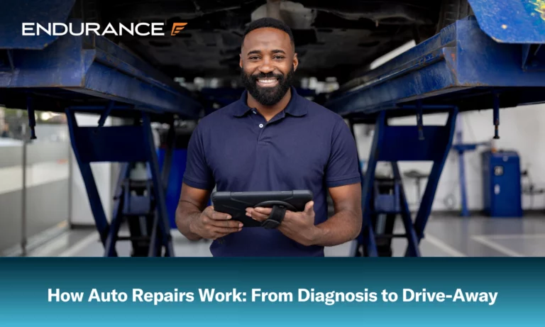 Mechanic working at a car garage using a digital tablet and smiling