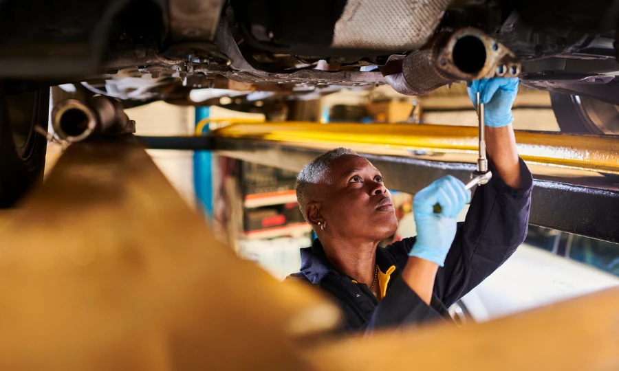 Female car mechanic working under a lifted vehicle
