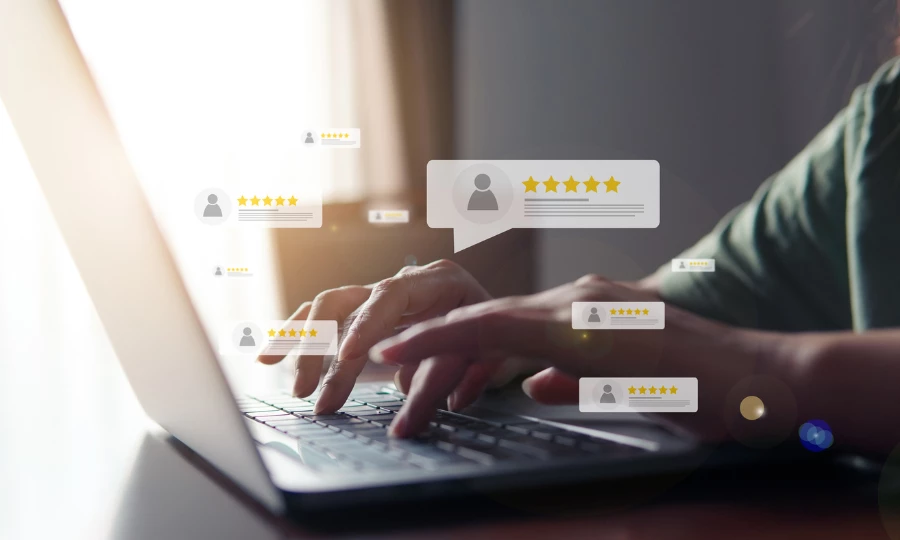 Hands typing on a laptop with 5-star review bubbles appearing