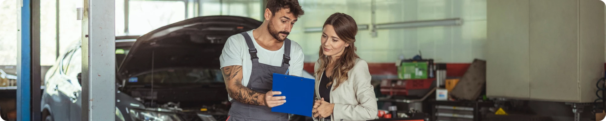 Mecánico y cliente conversando en el taller de reparación
