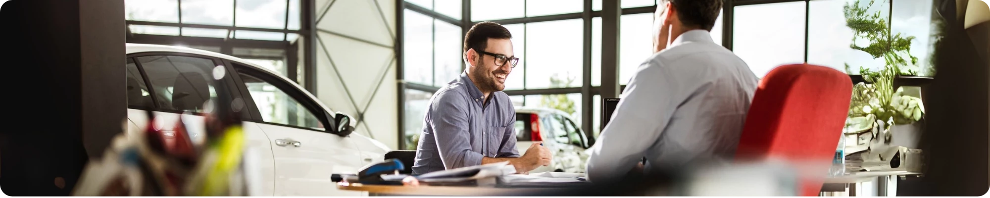 Hombre feliz hablando con un vendedor de coches en una sala de exposición