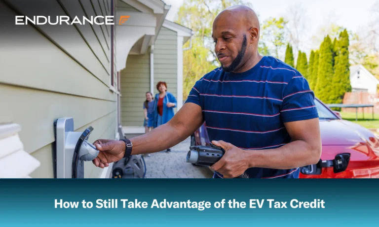A man holding an EV charger, ready to plug it into a red car outside
