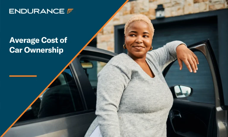 Young woman standing by an open car door wearing a gray sweater