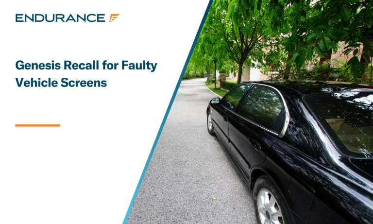 Un vehículo Genesis negro circulando por una carretera bordeada de árboles.