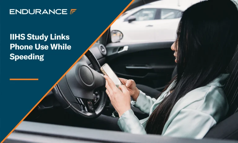Una mujer usa su teléfono inteligente mientras conduce su automóvil; el IIHS relaciona el uso del teléfono celular con el exceso de velocidad.